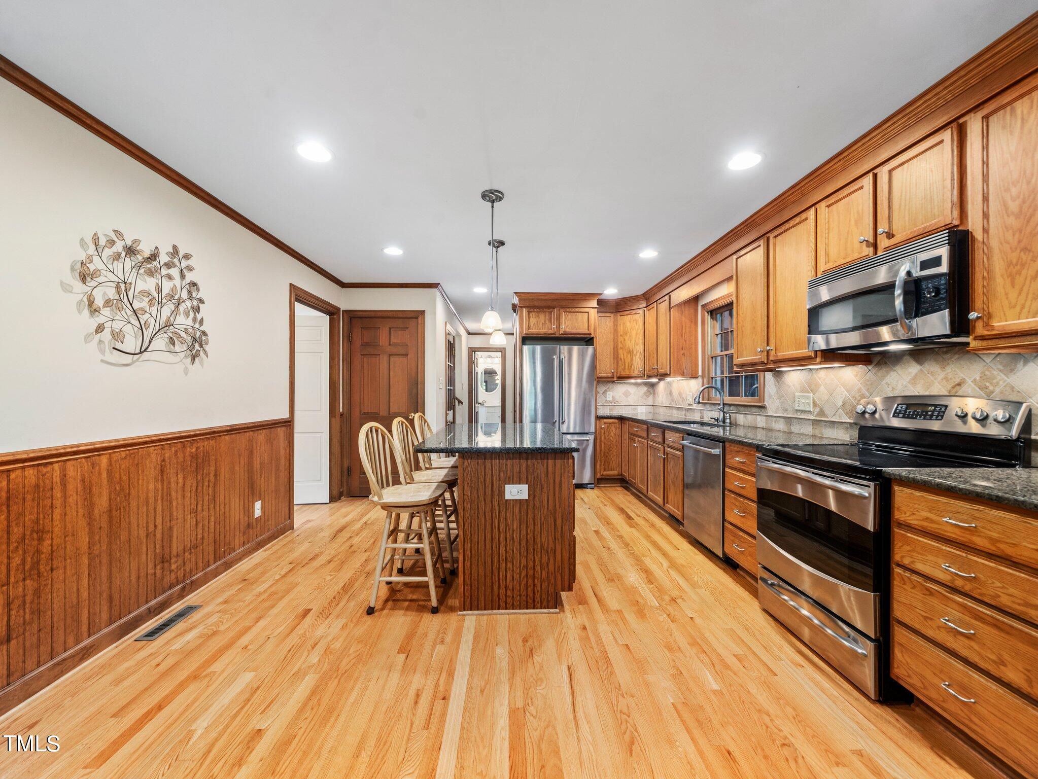 4205 Weaver Drive Raleigh, NC 27612 - Photo 15 of 48 a large kitchen with stainless steel appliances granite countertop a stove a sink dishwasher and a microwave with wooden floor