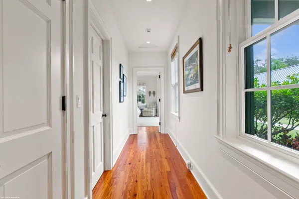 a view of a hallway with wooden floor and windows