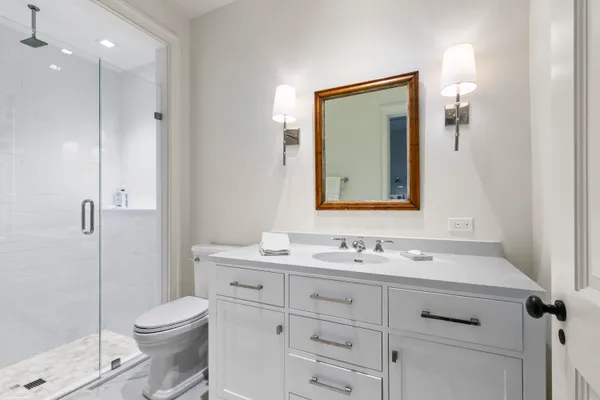 a bathroom with a toilet sink a mirror and shower