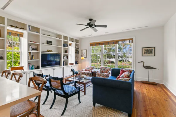 a living room with furniture floor to ceiling window hardwood floor and a flat screen tv