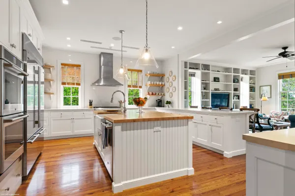 a large kitchen with stainless steel appliances granite countertop a stove a sink and a wooden floors