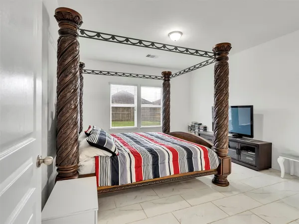 a bedroom with a bed and a flat tv screen on the dresser