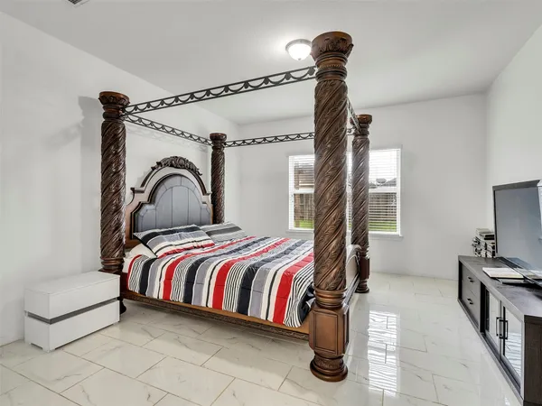 a bedroom with a bed and a flat tv screen on the dresser