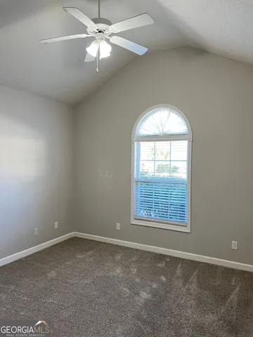 an empty room with a window and a fan