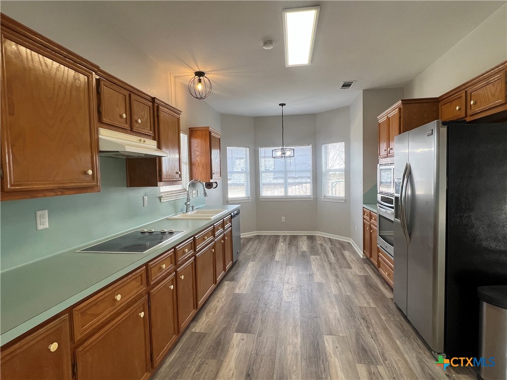 5899 Denmans Loop Belton, TX 76513 - Photo 10 of 35 a kitchen with stainless steel appliances granite countertop a refrigerator a sink dishwasher a stove and white countertops with wooden floor