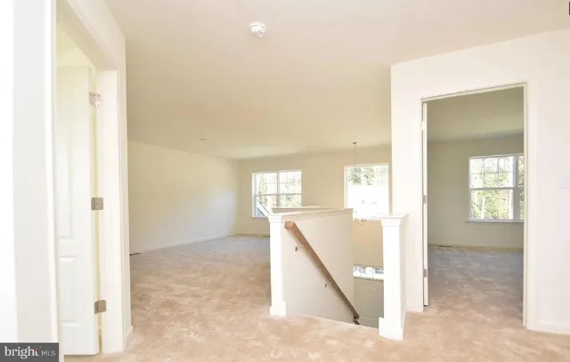 a view of a hallway to a room with wooden floor and windows