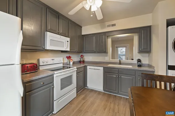 a kitchen with granite countertop a refrigerator a stove a sink and dishwasher with wooden floor