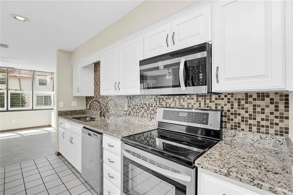 a kitchen with granite countertop a stove sink and microwave