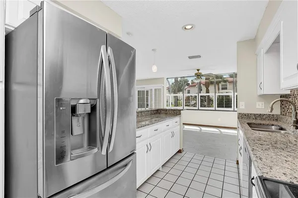 a kitchen with granite countertop a refrigerator and a stove top oven