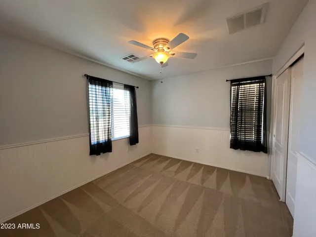 an empty room with windows and fan