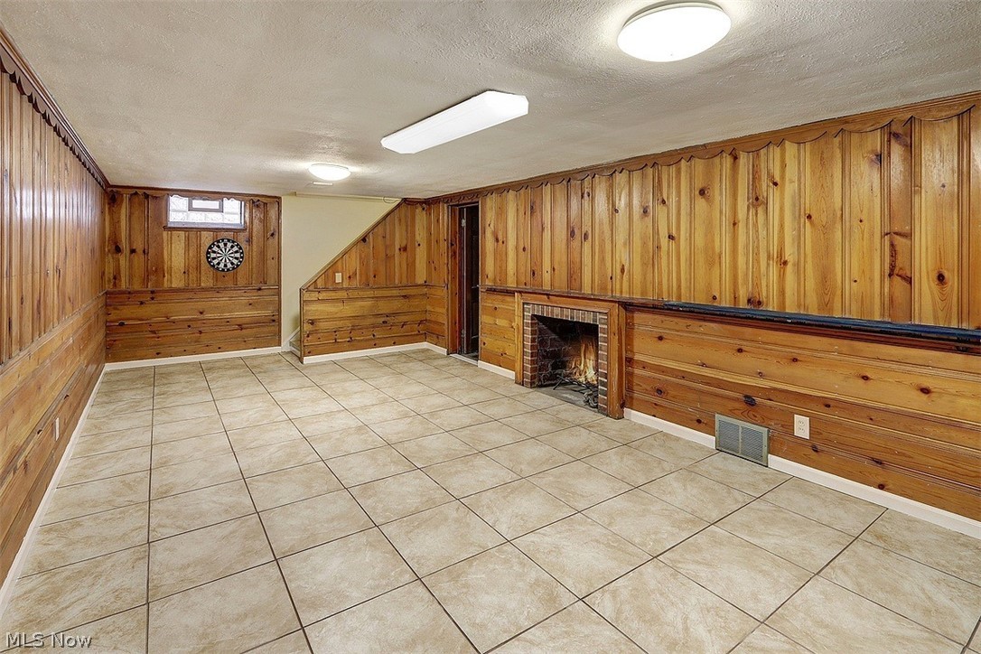 4457 Groveland Road University Heights, OH 44118 - Photo 21 of 24 The recreation room has ceramic tile floors and wood-paneled walls. The fire in the fireplace is the photographer's depiction. The current owner has not used it and does not guarantee that it works.