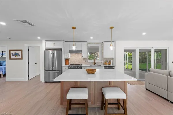 a kitchen with a dining table chairs refrigerator and wooden floor