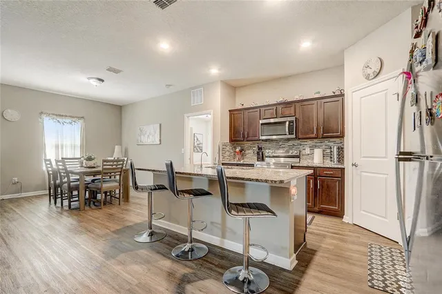 a large kitchen with stainless steel appliances granite countertop a sink stove and wooden cabinets