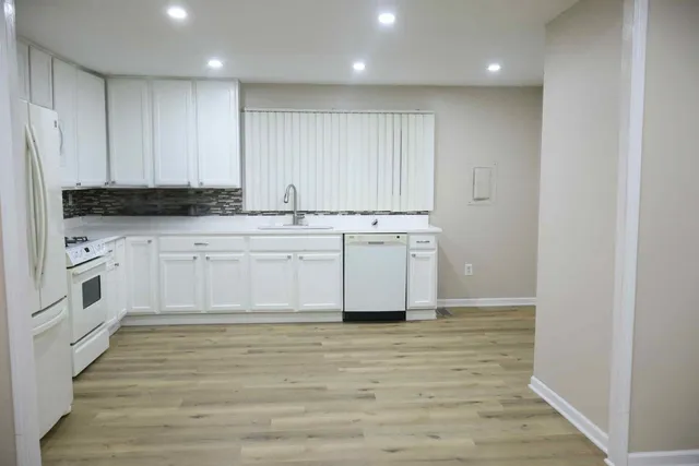 a white kitchen with granite countertop stainless steel appliances and cabinets
