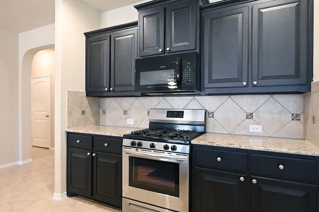 a kitchen with granite countertop cabinets and steel stove top oven