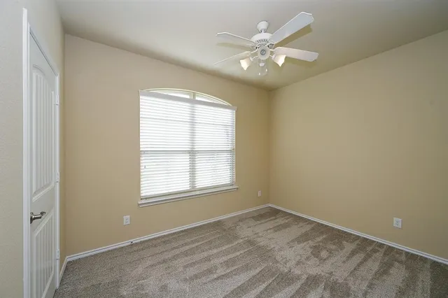 an empty room with chandelier fan and windows