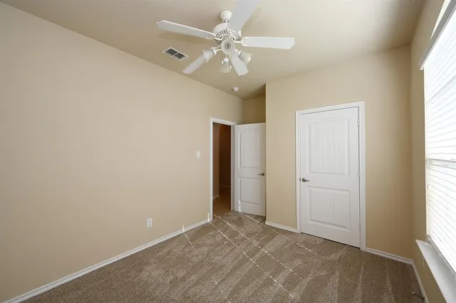 an empty room with windows and fan
