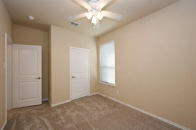 an empty room with windows and fan