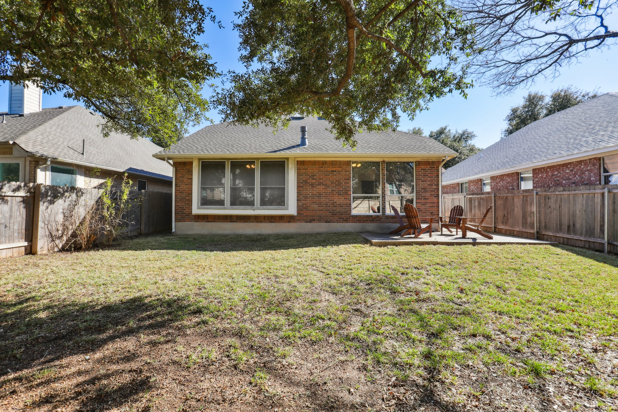 13541 Anarosa Loop Austin, TX 78727 - Photo 24 of 27 Brick exterior with multiple windows and a concrete patio