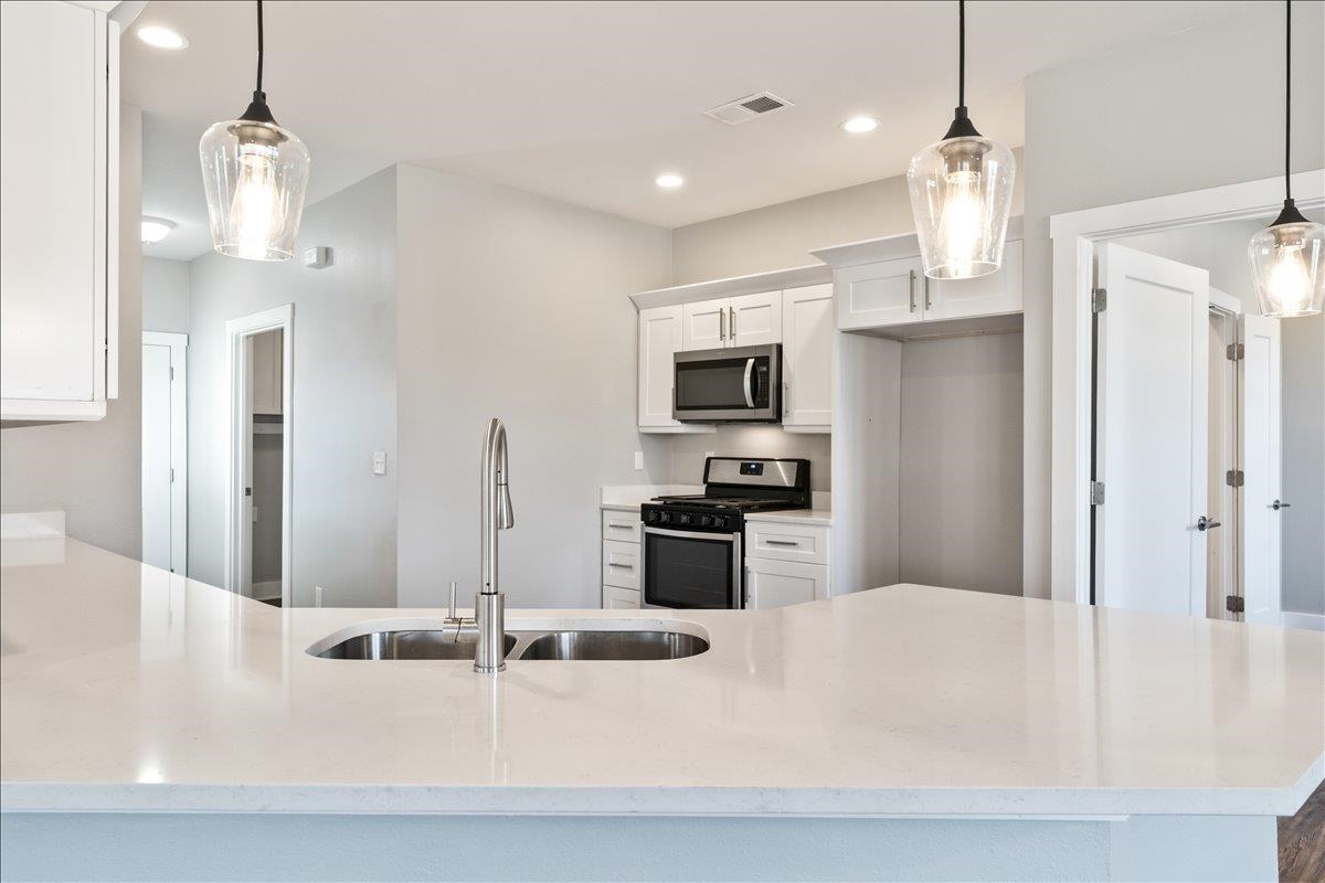 447 Abbey Road, Unit A Munford, TN 38058 - Photo 3 of 30 a kitchen with stainless steel appliances kitchen island granite countertop a refrigerator a sink dishwasher a stove oven a white table and chairs with wooden floor
