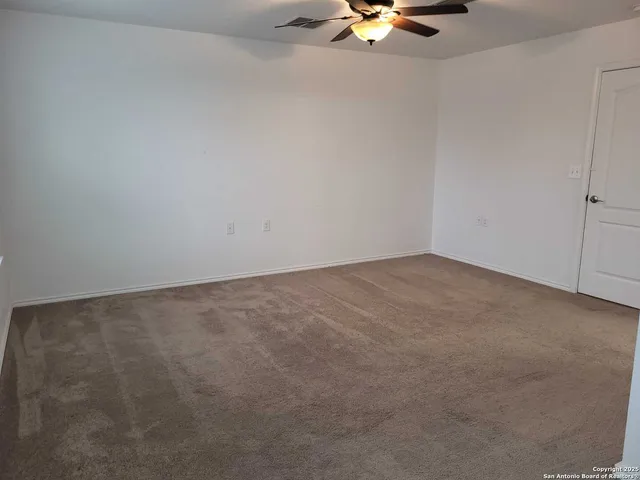 an empty room with a chandelier fan and windows