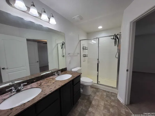a bathroom with a granite countertop sink a toilet and shower