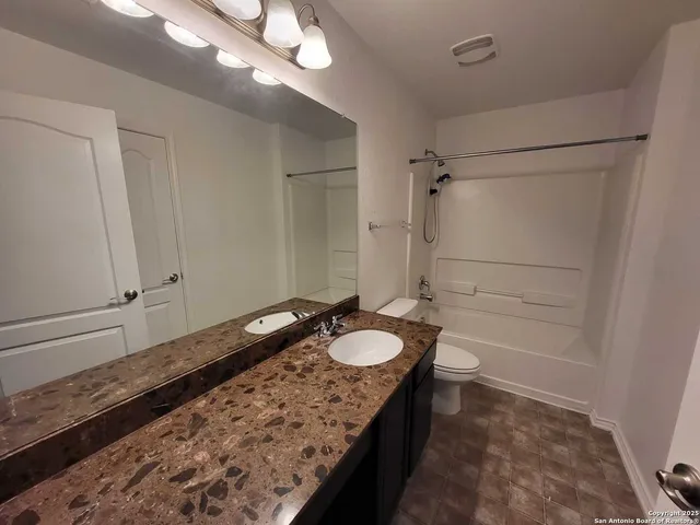 a bathroom with a granite countertop toilet and a sink