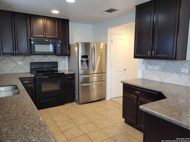 a kitchen with granite countertop stainless steel appliances and refrigerator