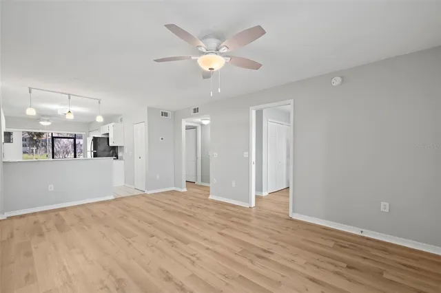a view of an empty room with wooden floor and a ceiling fan