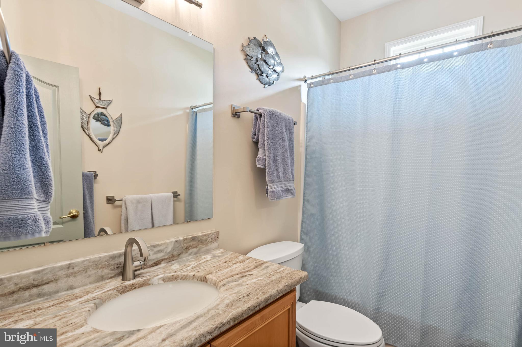 20234 Whitehead Circle, Unit 100 Rehoboth Beach, DE 19971 - Photo 23 of 40 a bathroom with a granite countertop sink toilet and shower