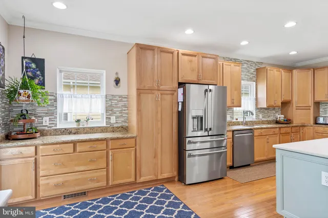 a kitchen with stainless steel appliances granite countertop a refrigerator a stove and white cabinets with wooden floor