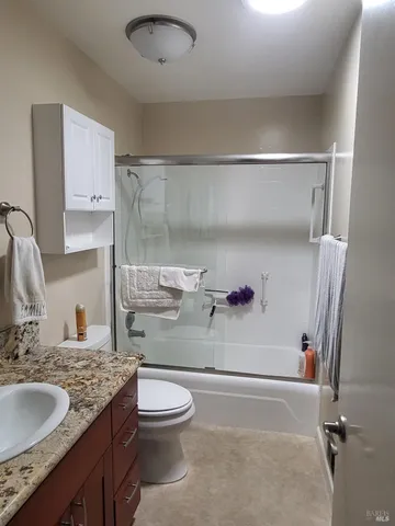 a bathroom with a granite countertop sink a toilet and shower