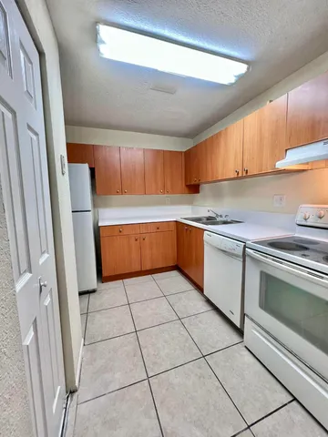a kitchen with granite countertop a sink cabinets and stainless steel appliances