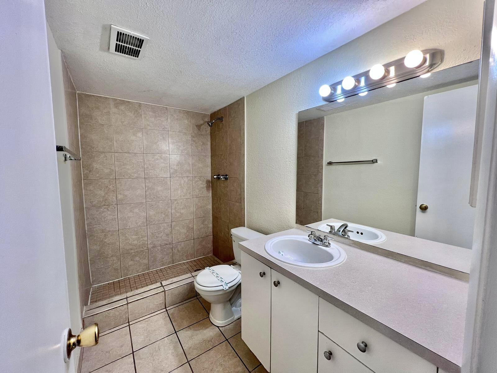 415 Executive Center Drive, Unit 213 West Palm Beach, FL 33401 - Photo 11 of 23 a bathroom with a sink a toilet a mirror and shower