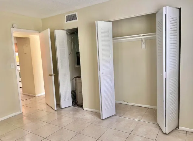 a view of an empty room with closet and a fireplace