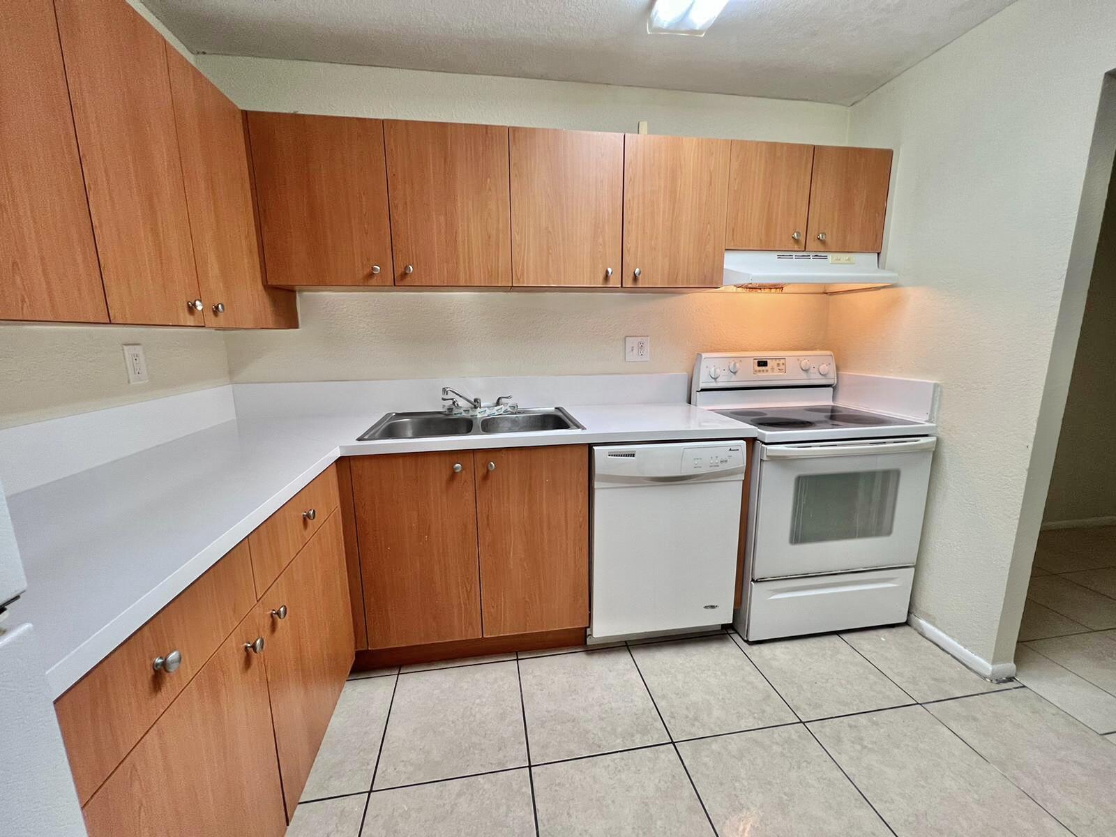 415 Executive Center Drive, Unit 213 West Palm Beach, FL 33401 - Photo 2 of 23 a kitchen with a stove sink and cabinets