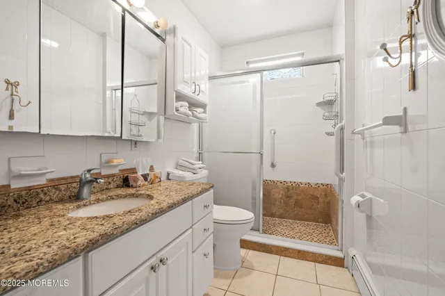a bathroom with a granite countertop sink a toilet and shower