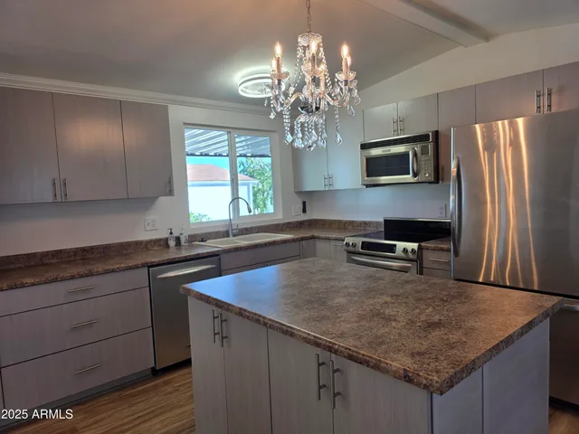 a kitchen with kitchen island granite countertop stainless steel appliances a sink stove and refrigerator