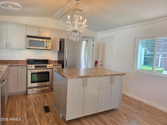 a kitchen with granite countertop a sink cabinets stainless steel appliances and a window
