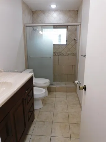 a bathroom with a granite countertop shower a toilet and a shower
