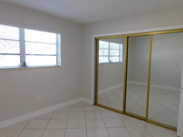 a view of an empty room with window and chandelier fan