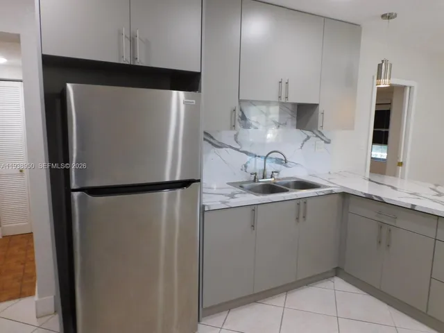 a kitchen with a sink a refrigerator and cabinets