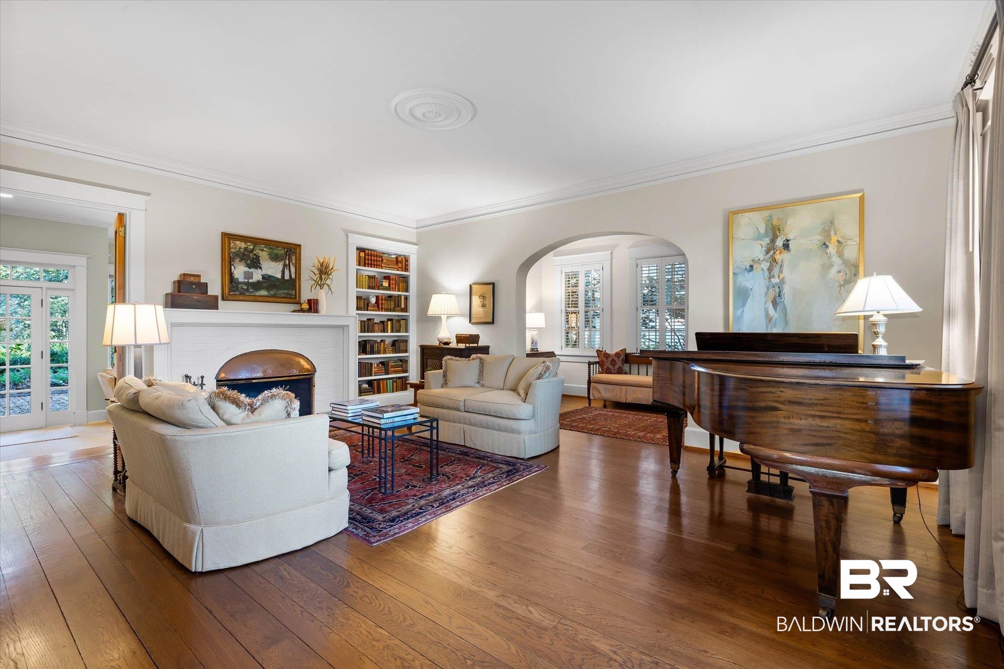 2 Westgate Road Mobile, AL 36608 - Photo 6 of 63 Living area featuring wood-type flooring, crown molding, arched walkways, built in shelves, and a brick fireplace