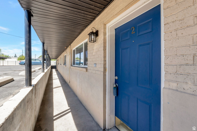 434 South 700 West, Unit 2 Provo, UT 84601 - Photo 2 of 15 Entryway featuring a bright blue paneled door with gold-toned numbering, brick facade, and an exterior lantern sconce