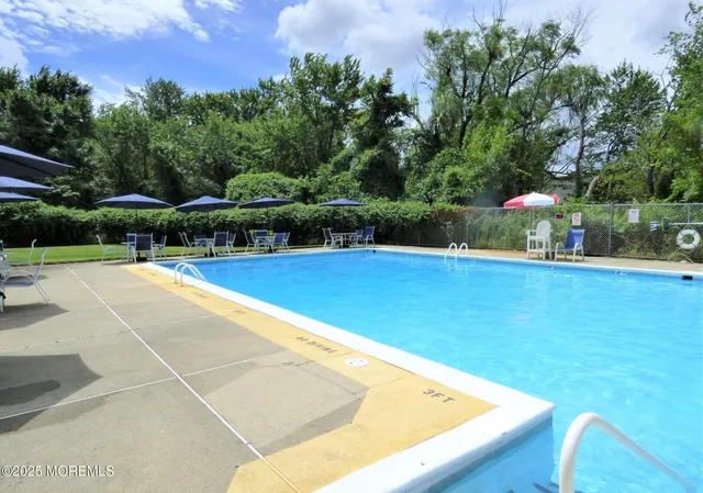 a view of swimming pool with seating space and trees in the background