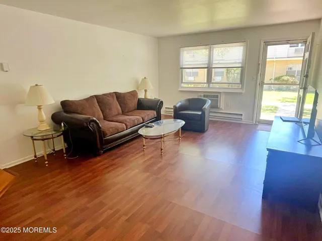 a living room with furniture large window and wooden floor
