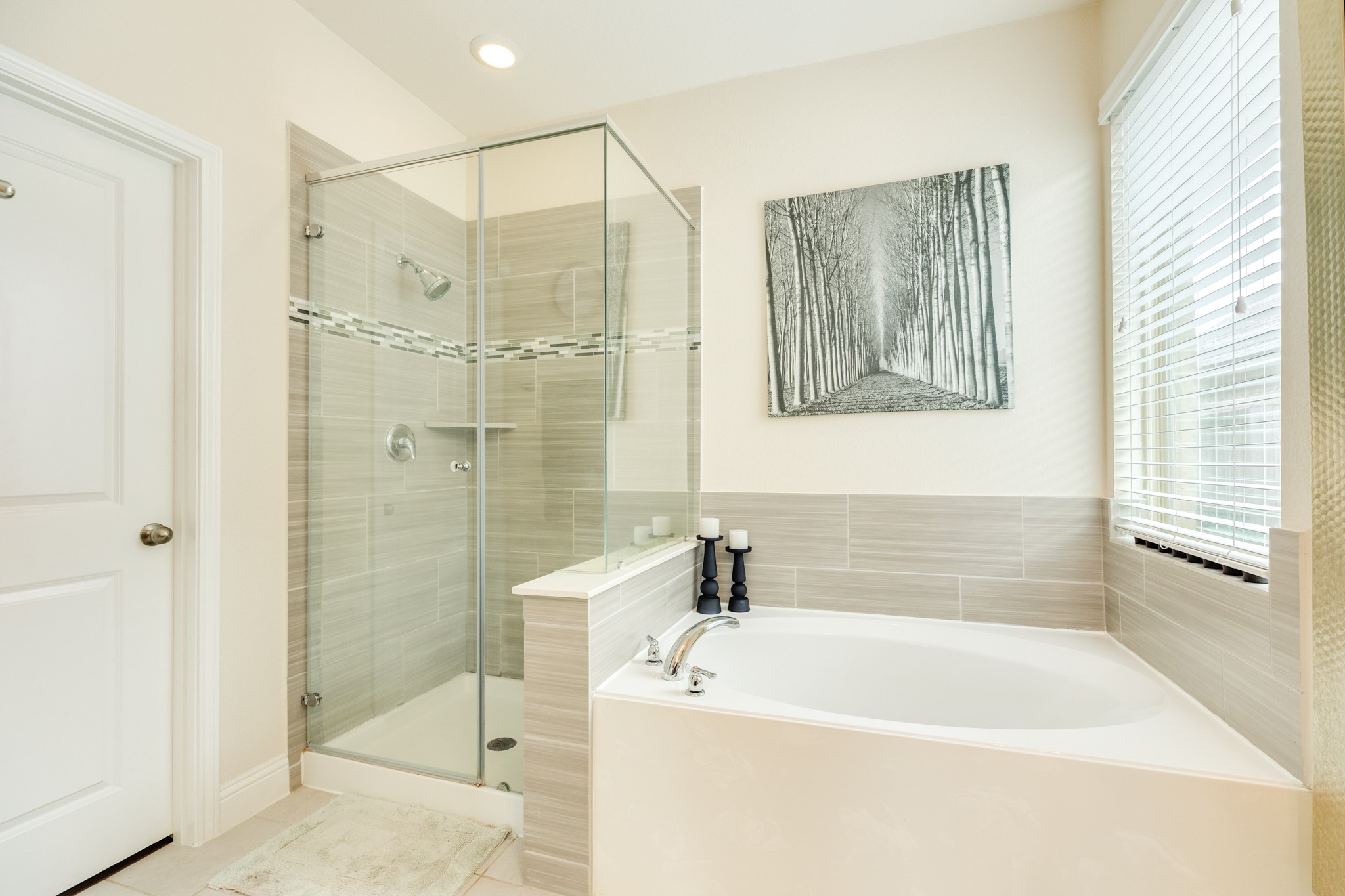 3519 Bay Drive Rosharon, TX 77583 - Photo 22 of 49 Stunning spa-inspired primary bathroom featuring a sleek glass walk-in shower with floor-to-ceiling tile accents and a luxurious deep soaking tub perfectly positioned beneath a window for natural light.