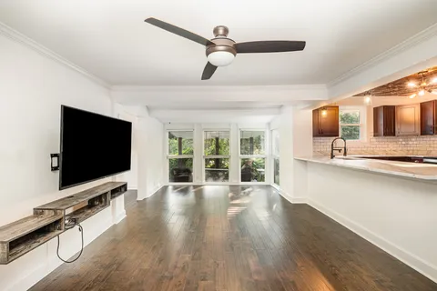 a living room with furniture flat screen tv and a ceiling fan