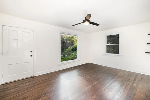 a view of an empty room with wooden floor and a window
