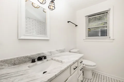 a bathroom with a granite countertop sink toilet and a mirror